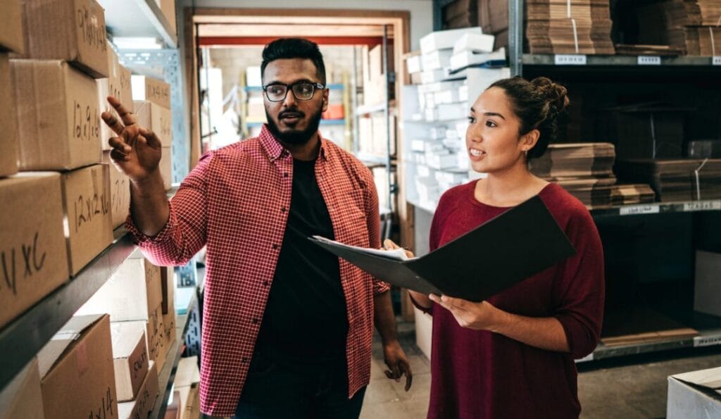 Two business owners in a warehouse looking at boxes